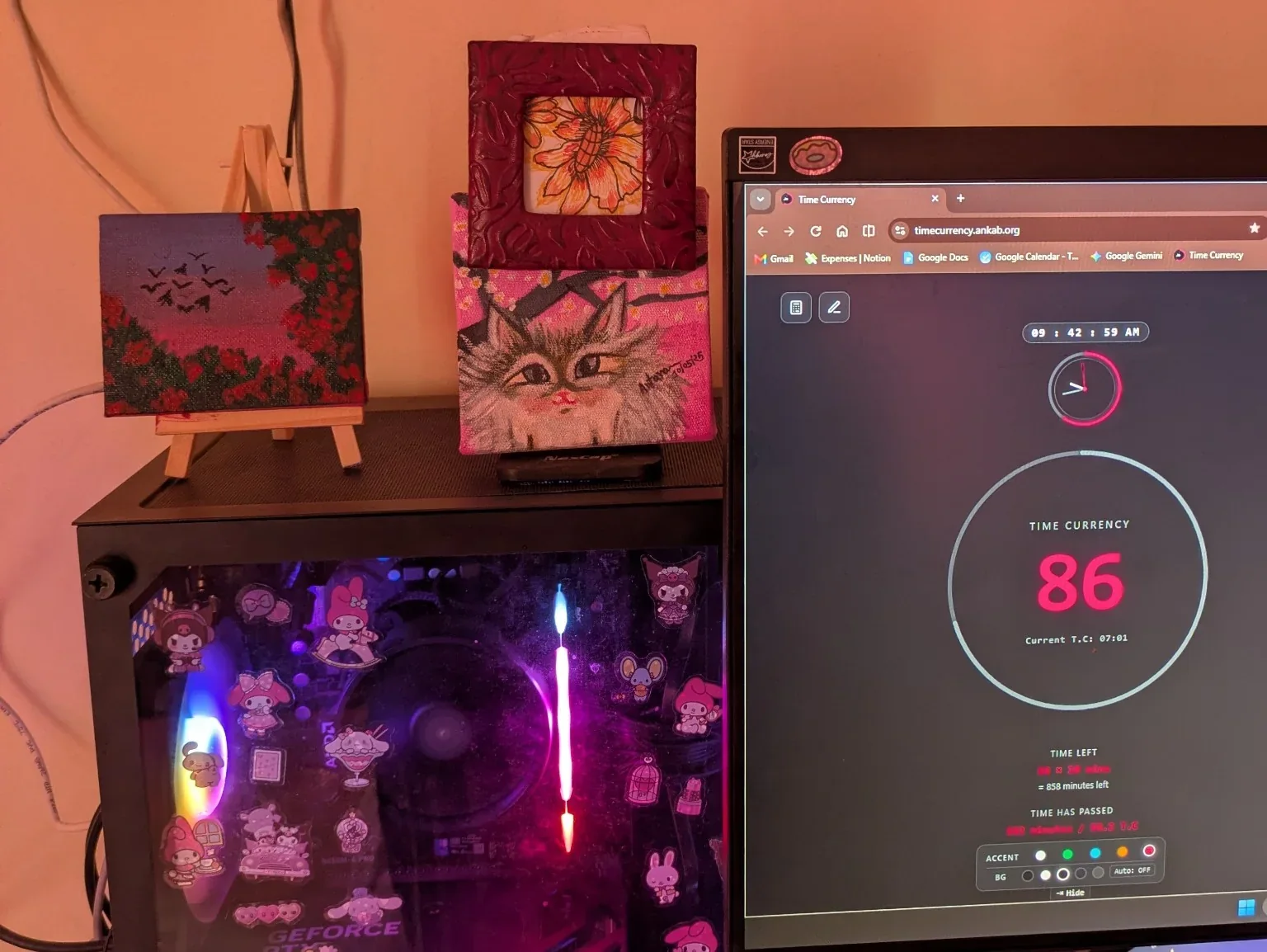 A creative desk with artwork and the Time Currency project open on a monitor